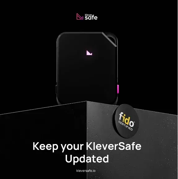Black KleverSafe hardware wallet with a glowing pink logo on a sleek pedestal, featuring FIDO certification and update reminder