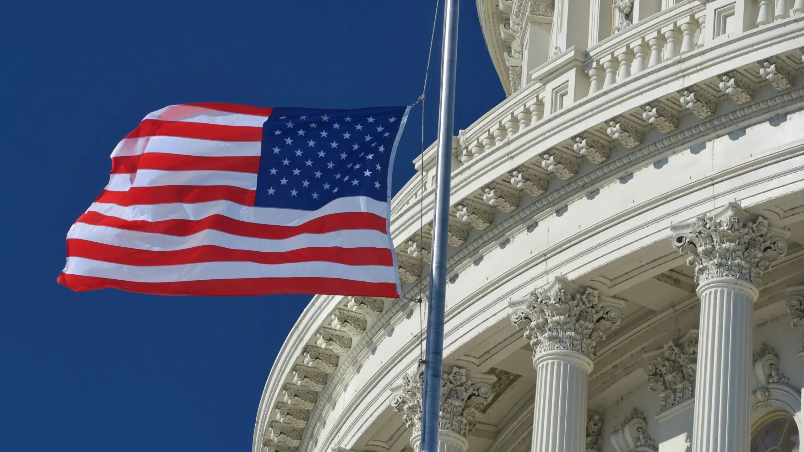 U.S. flag waving in front of the Capitol in Washington D.C., symbolizing American legislative authority and key decisions affecting global financial and crypto markets.