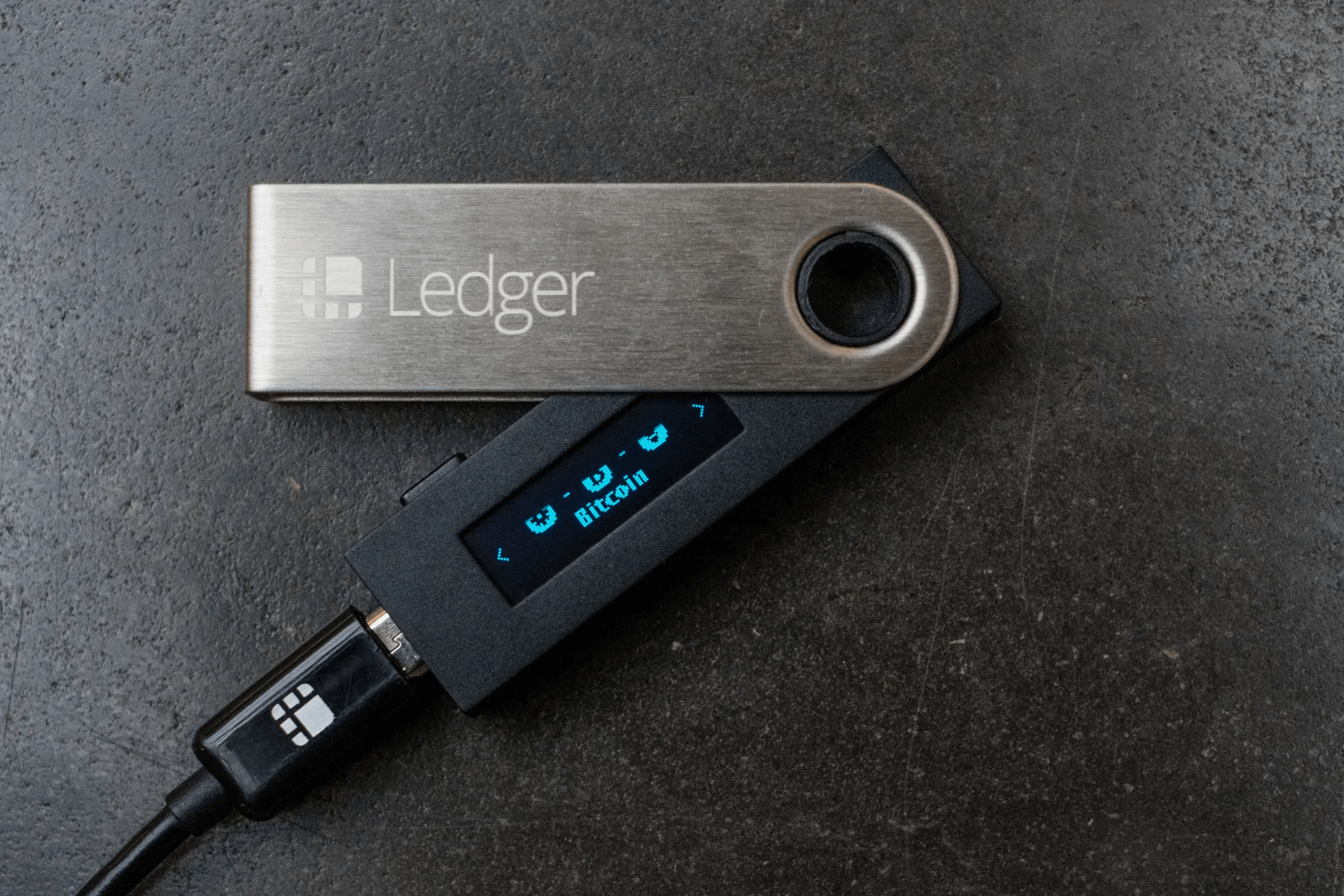Ledger hardware wallet connected via USB, displaying Bitcoin on screen.